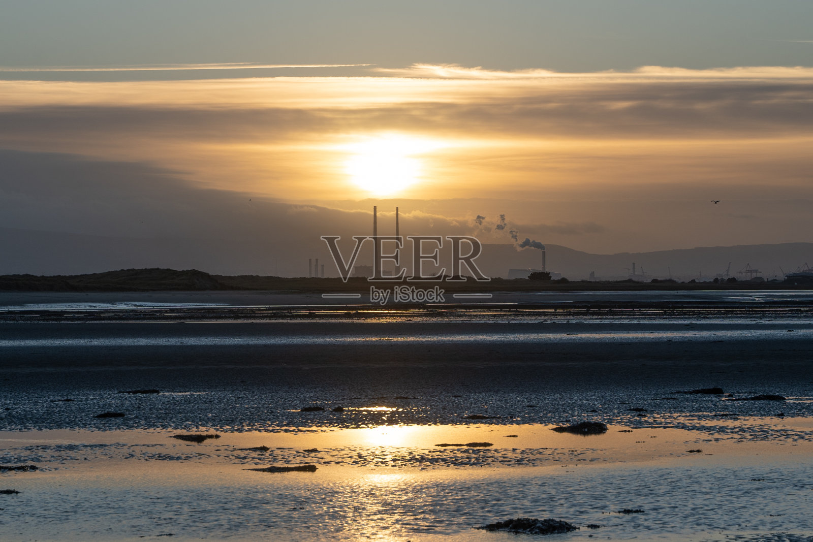 都柏林湾的日落和远处的Poolbeg烟囱照片摄影图片