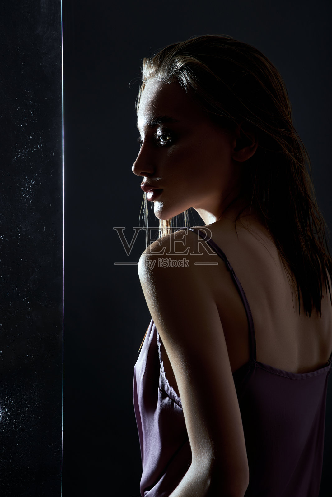 美丽的女人，湿漉漉的头发靠近玻璃在雨点。天然化妆品和化妆品照片摄影图片