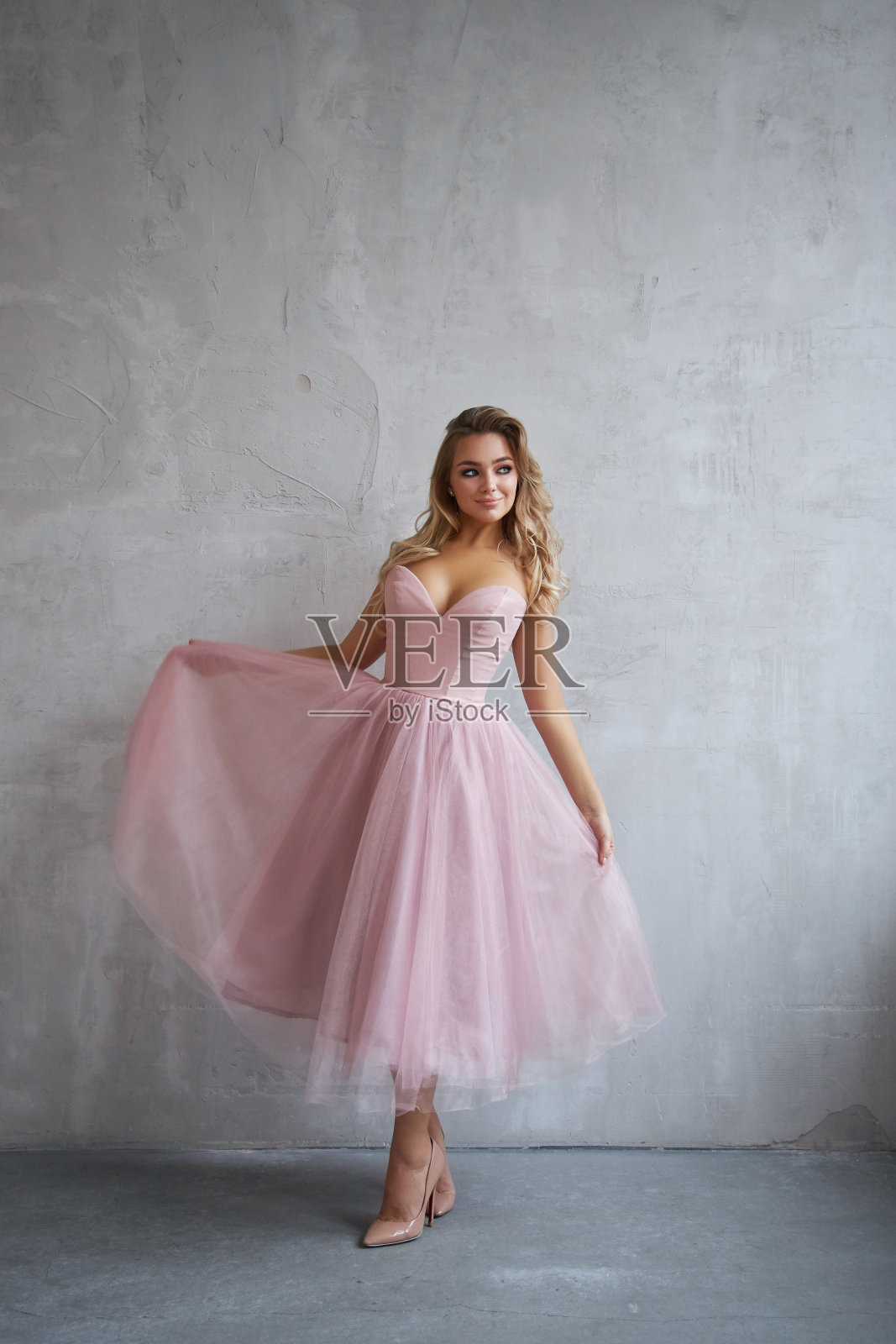 性感时尚的漂亮女人穿着衣服正靠墙站着。完美的妆容，浪漫的金发女人肖像照片摄影图片