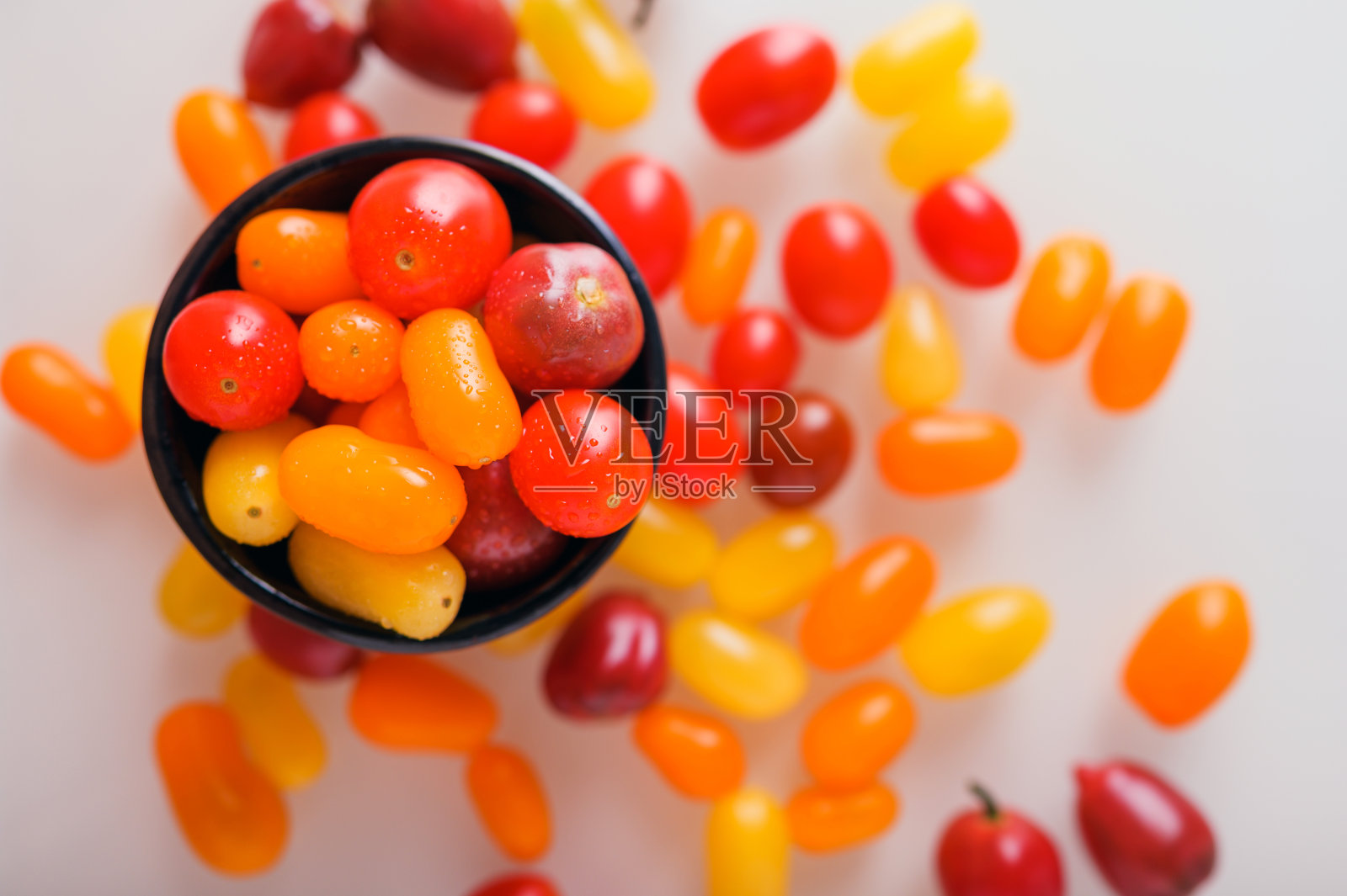 白色和木制背景上的各种五颜六色的樱桃番茄。创意设计，美丽的灯光。照片摄影图片