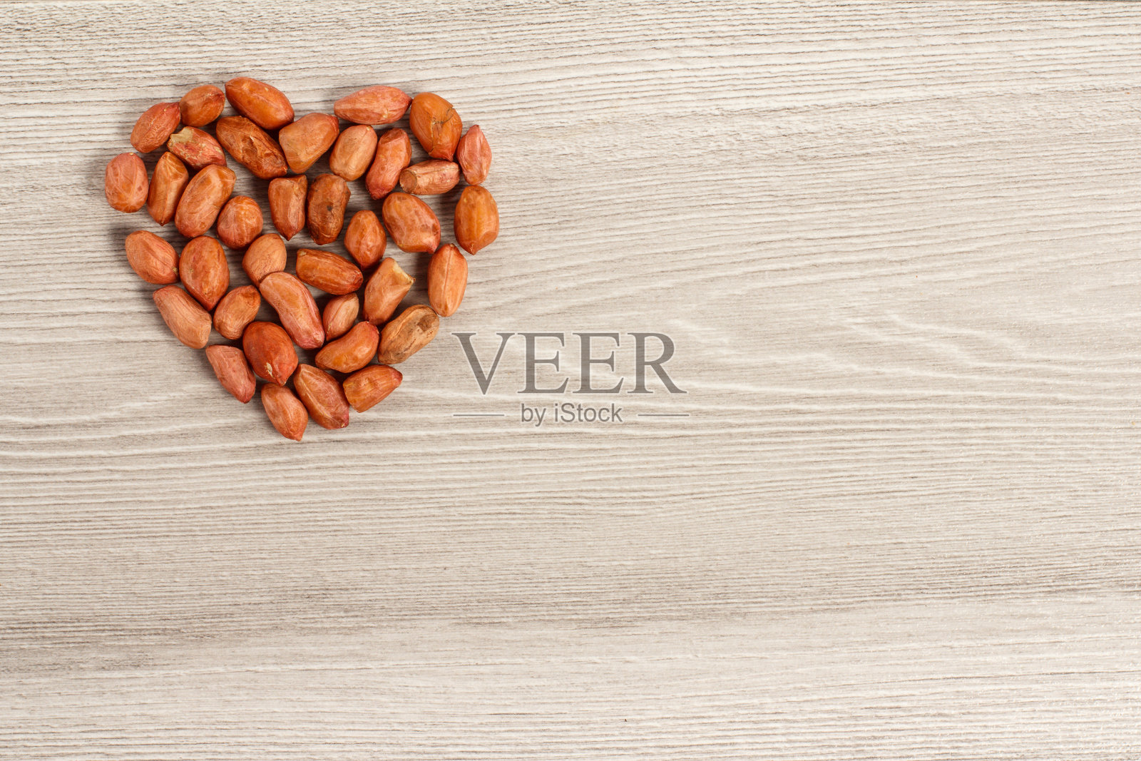 心形的花生放在灰色的木板上照片摄影图片
