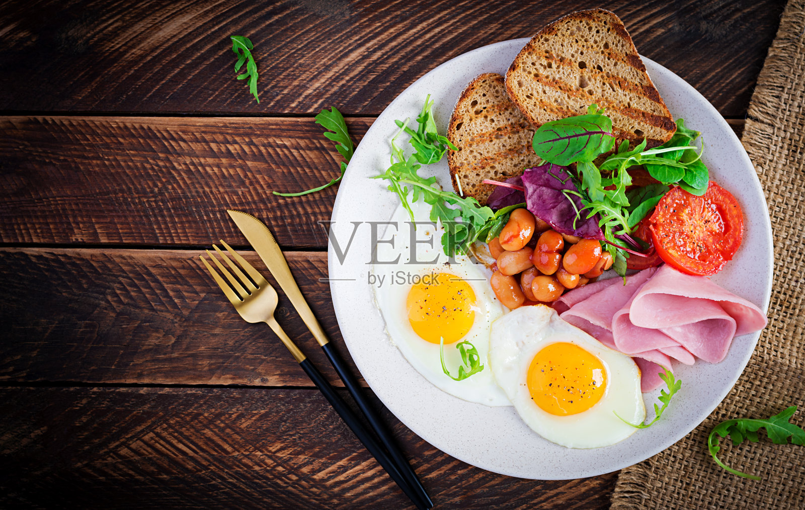 英式早餐-煎蛋，豆子，西红柿，香肠，火腿和吐司。俯视图，平躺，头顶照片摄影图片