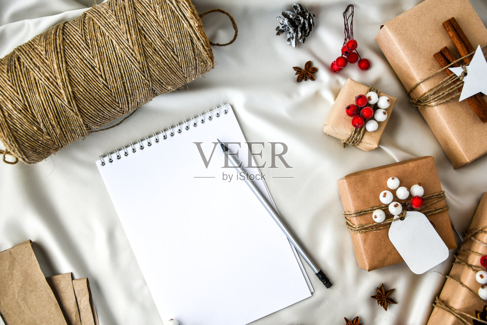 零浪费的圣诞文字与礼物装饰在香槟色的丝绸背景。笔记本空拷贝空间。环保包装礼品与标签从工艺纸板照片摄影图片