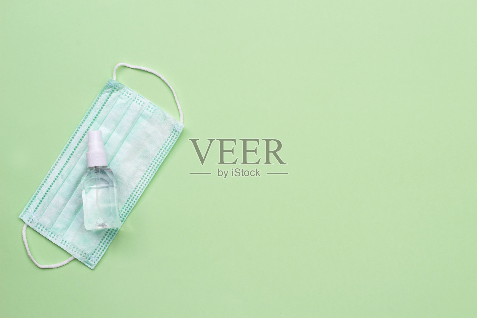 医用口罩和洗手液，绿色背景。流行的概念。本空间照片摄影图片