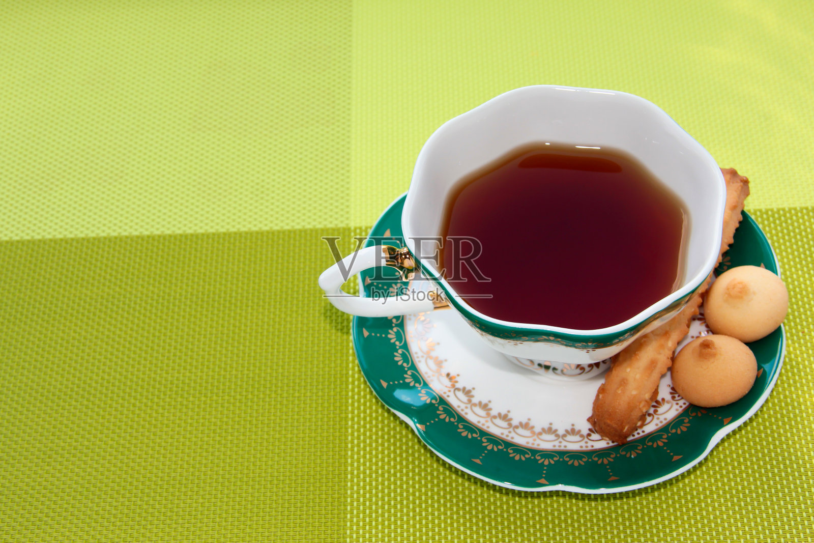 在明亮的背景下，一杯配有甜糕点的茶。照片摄影图片