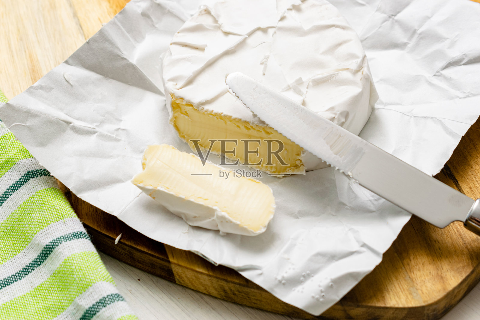 木制背景上的圆形卡门贝尔奶酪。照片摄影图片