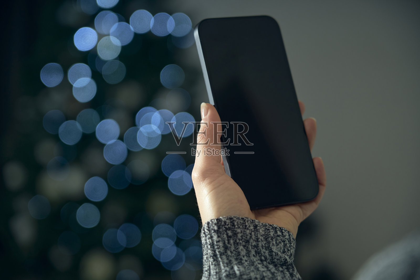 一名年轻女子在自己的客厅里用智能手机与朋友进行在线社交、祝福和庆祝。照片摄影图片