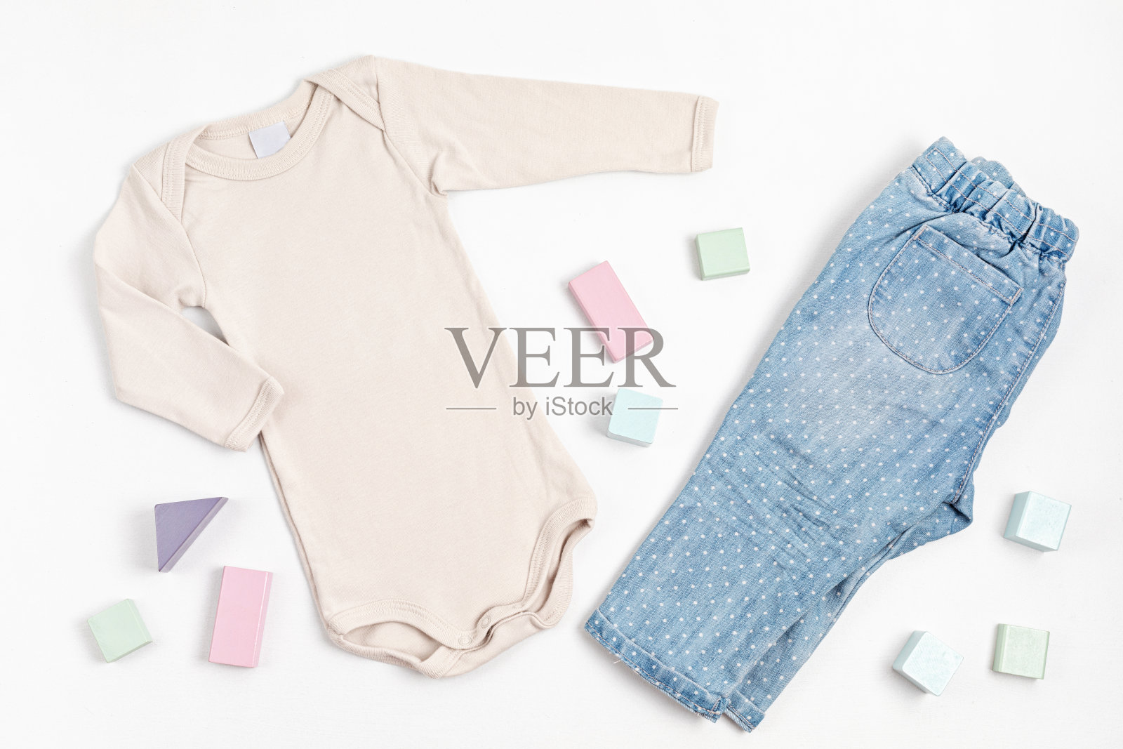 组成与婴儿米色紧身衣，牛仔裤，和玩具积木在白色的背景。中性童装照片摄影图片