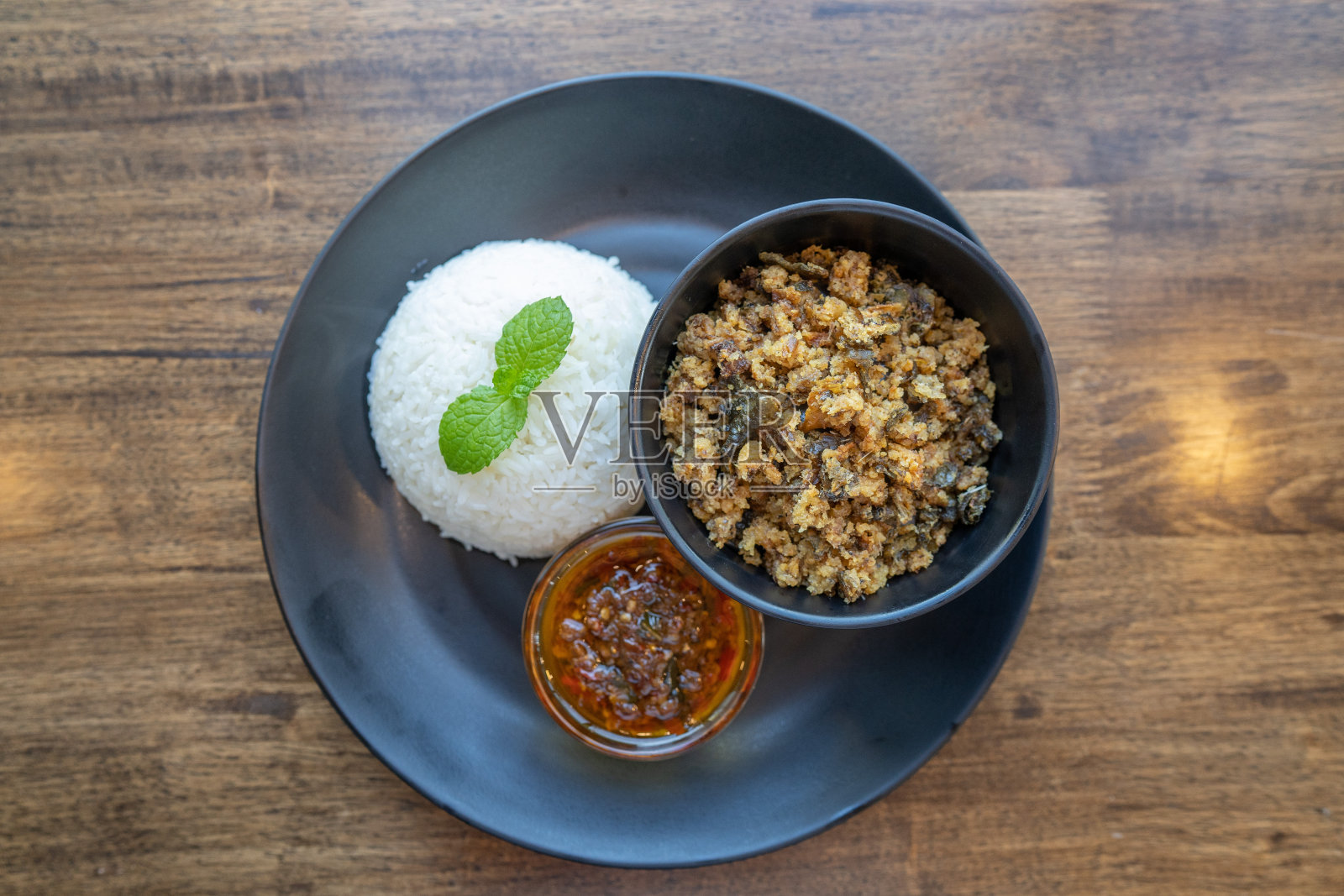 传统的泰国食物被称为“Yum Pla Duk Foo”，是一种经典的泰国餐，包括切碎的炒鲶鱼、新鲜的干辣椒和其他食材与米饭一起食用。有选择性的重点。照片摄影图片