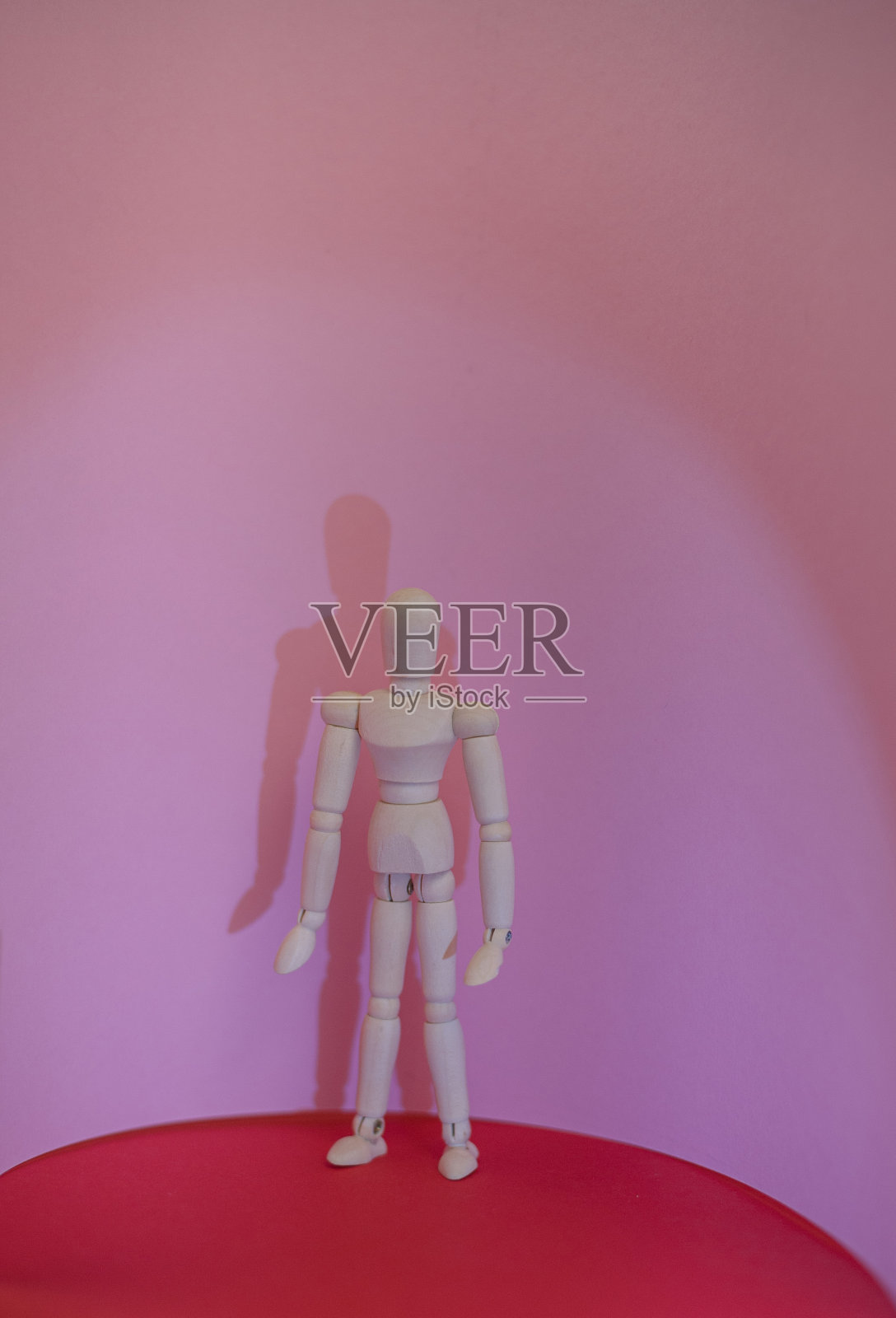 木头人站在红色和粉红色的背景上照片摄影图片