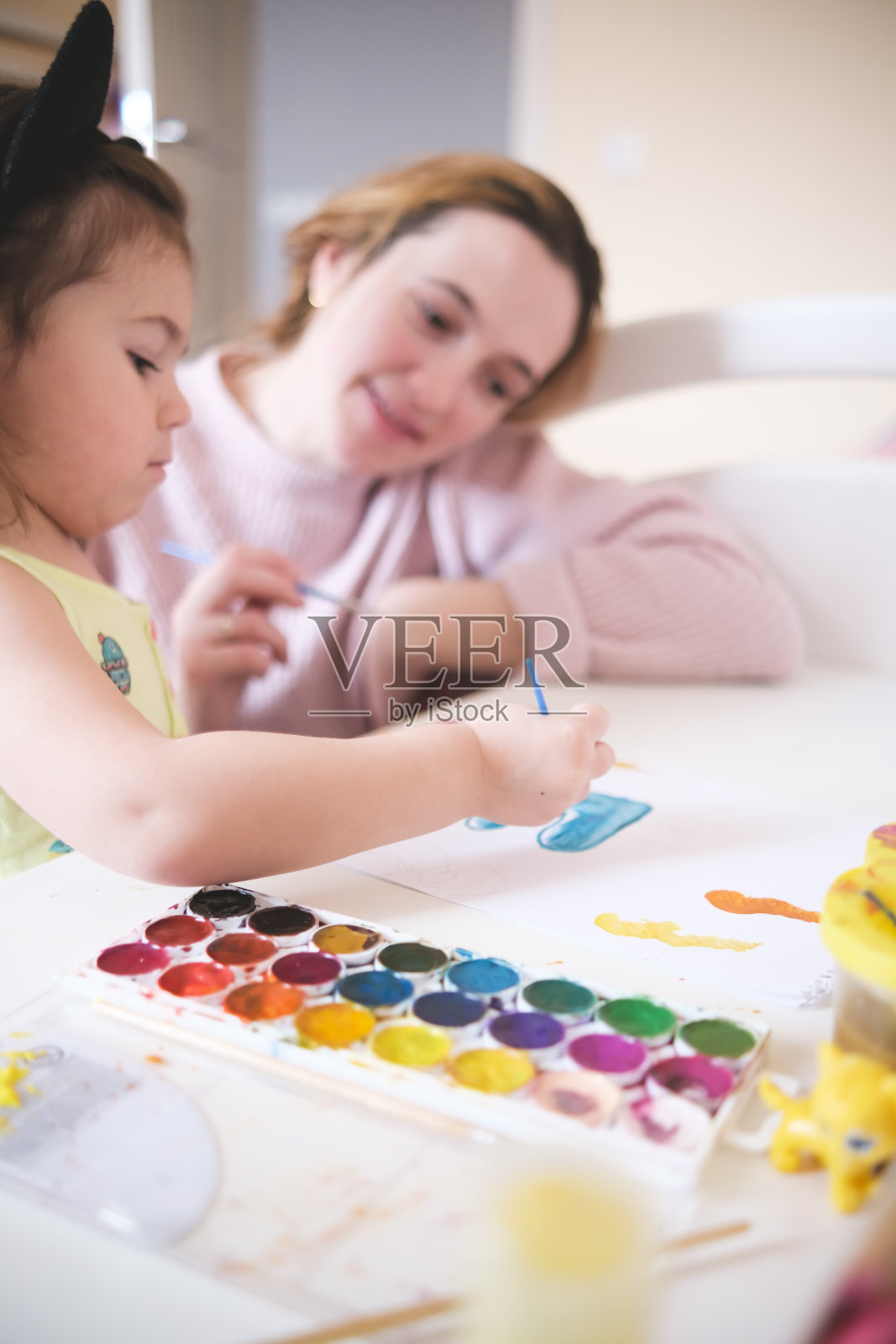 妈妈和女儿在家里的白色桌子上用水彩笔作画照片摄影图片