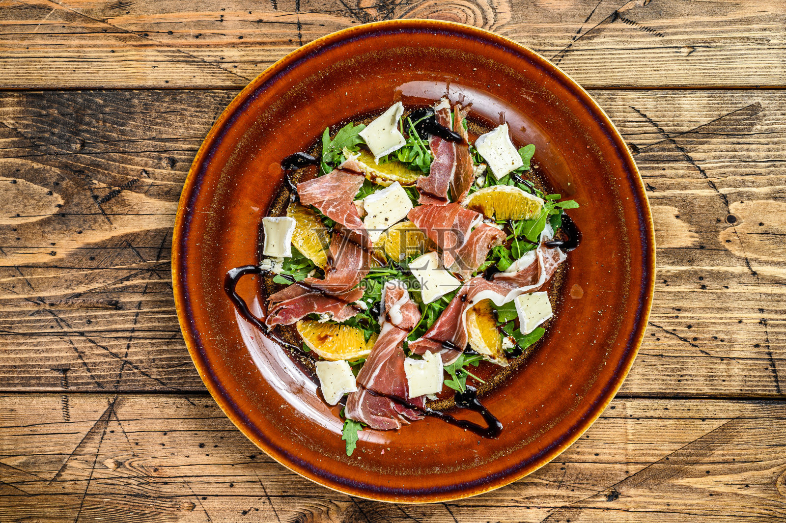 沙拉配意大利火腿，帕尔玛火腿，帕尔玛芝士，芝麻菜和橘子。木制背景。俯视图照片摄影图片