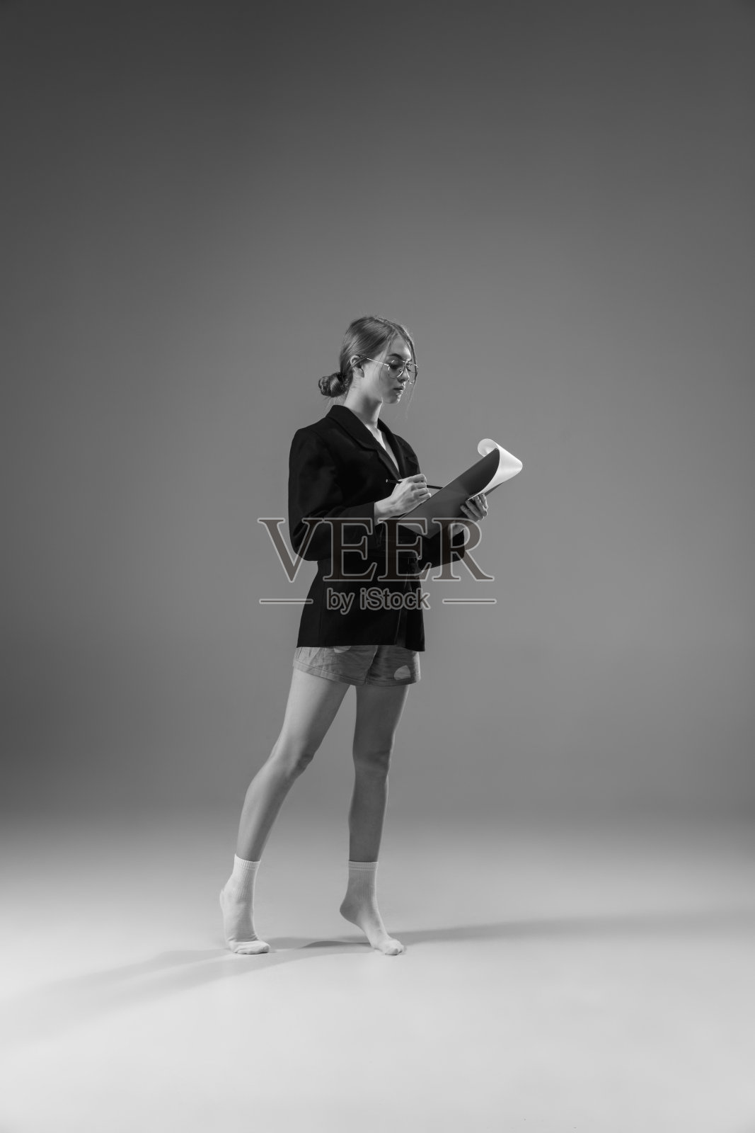 年轻、时尚、时髦的女性穿着夹克和袜子在家工作。保温期间的时尚是冠状病毒大流行的原因照片摄影图片