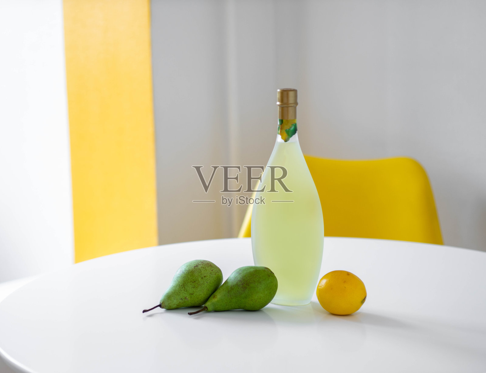 白色桌子上的瓶子的特写。酒喝。梨和柠檬。照片摄影图片