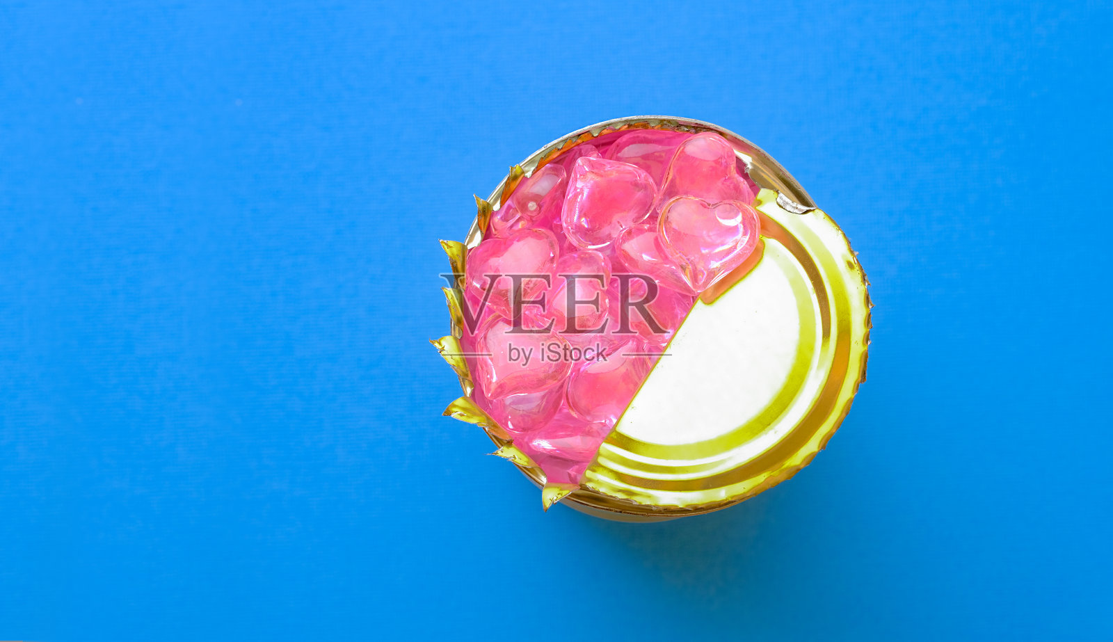 粉红色的心在一个罐头里面在蓝色的背景。概念:封闭的感觉。假的感情。破碎的心。照片摄影图片