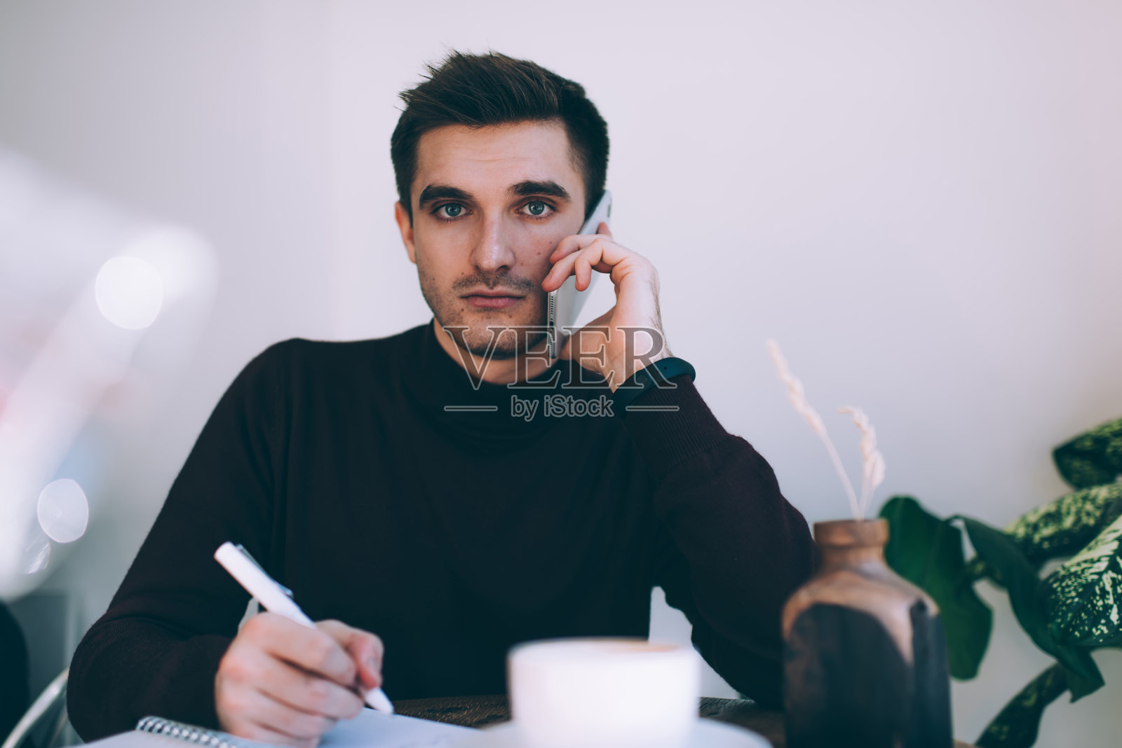 严肃的男性经理在创意工作空间远程工作时用智能手机讲话照片摄影图片