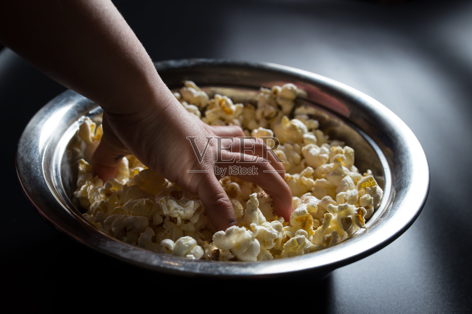 手把爆米花。吃爆米花。电影在家里。儿童快餐照片摄影图片