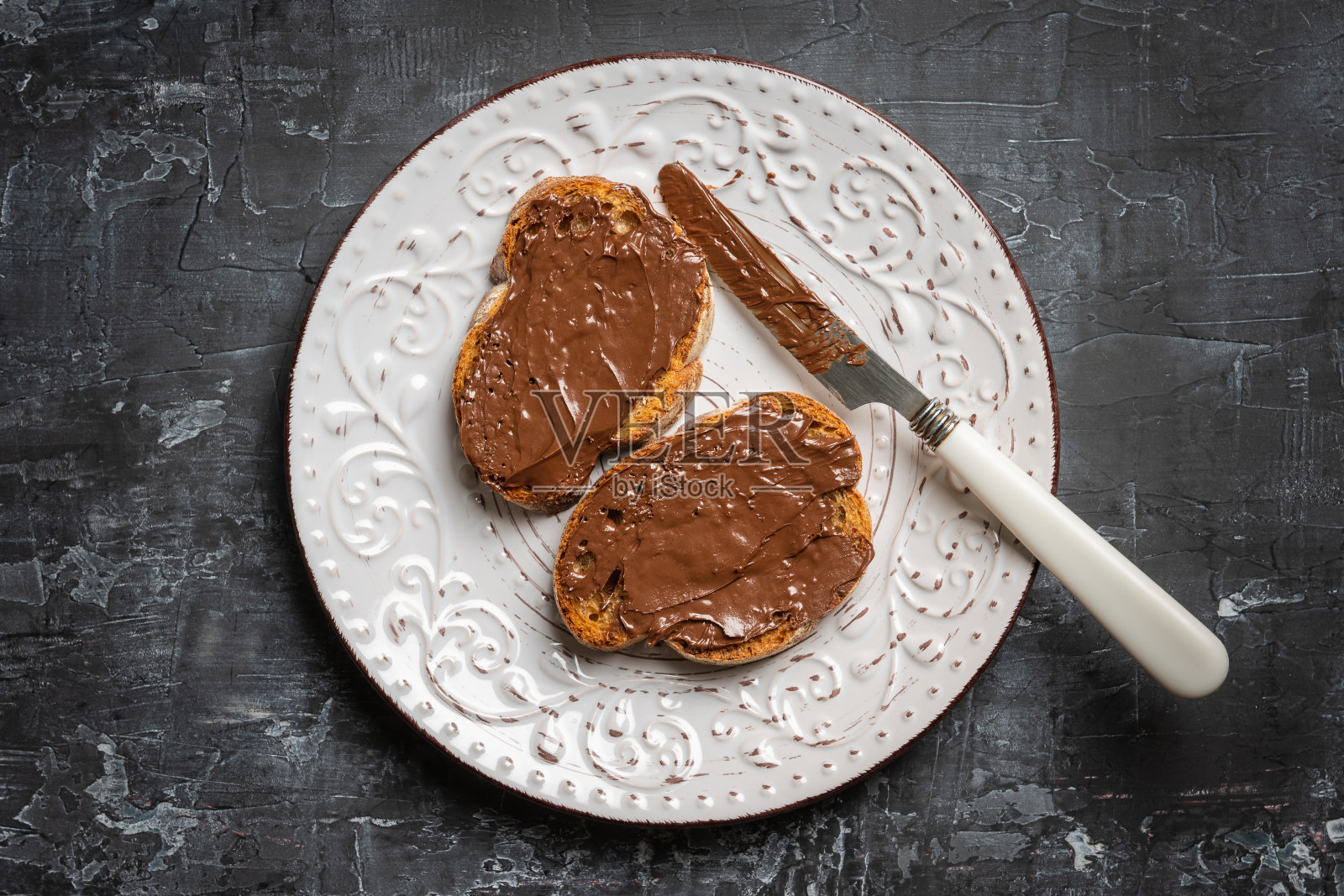厨房桌子上的早餐是一片自制的巧克力奶油面包。有选择性的重点。景深浅。照片摄影图片