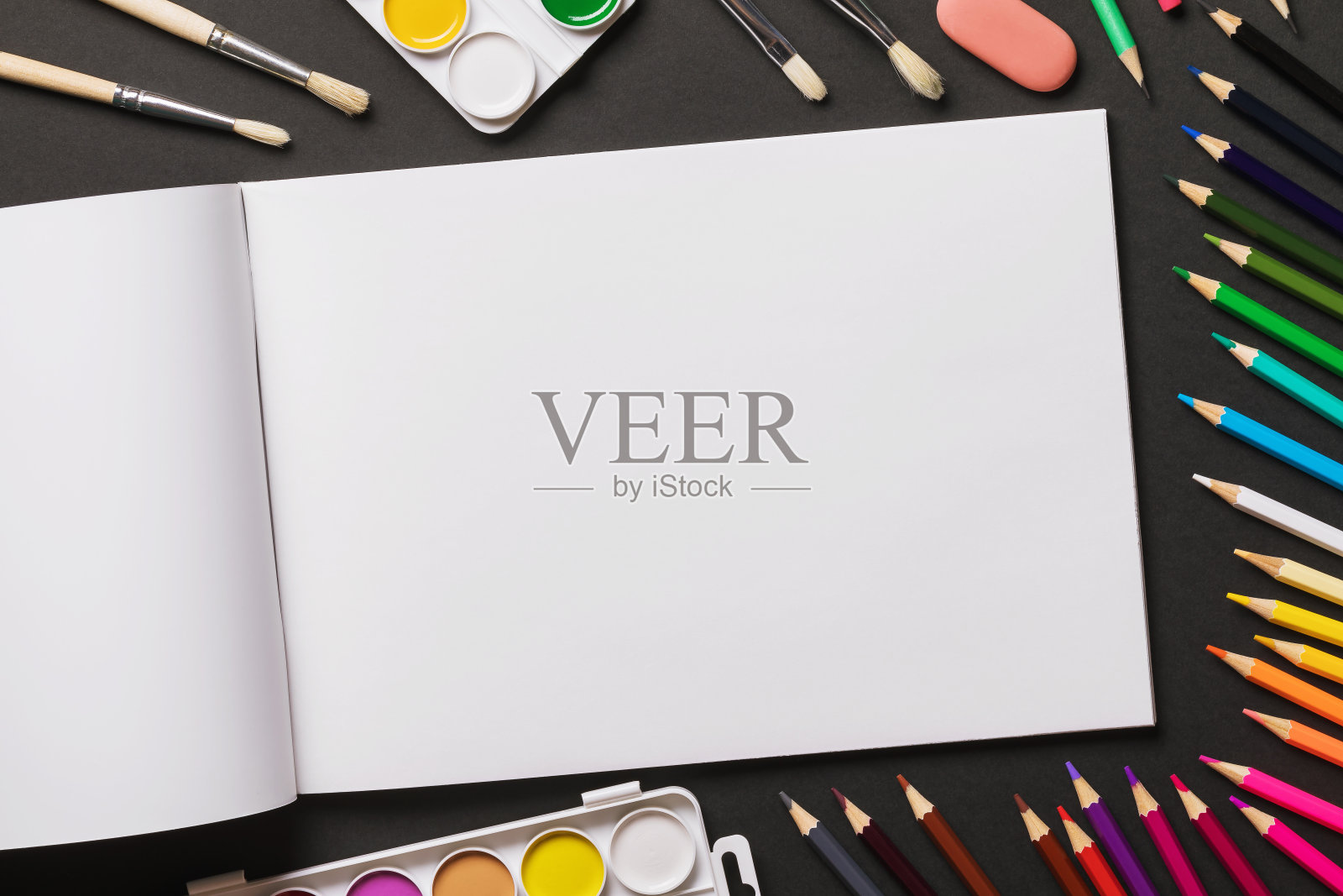 水彩颜料，画笔，彩色铅笔和速写本在一个黑暗的背景与复制空间，俯视图照片摄影图片