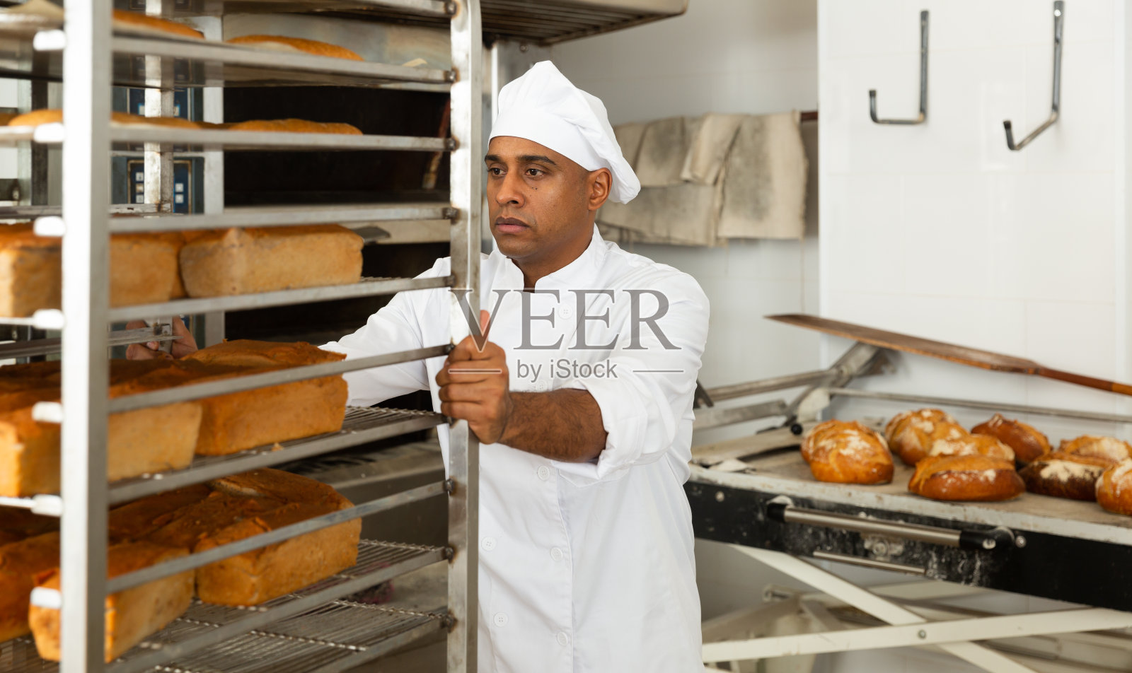 自信的面包师推着一辆手推车装着面包照片摄影图片