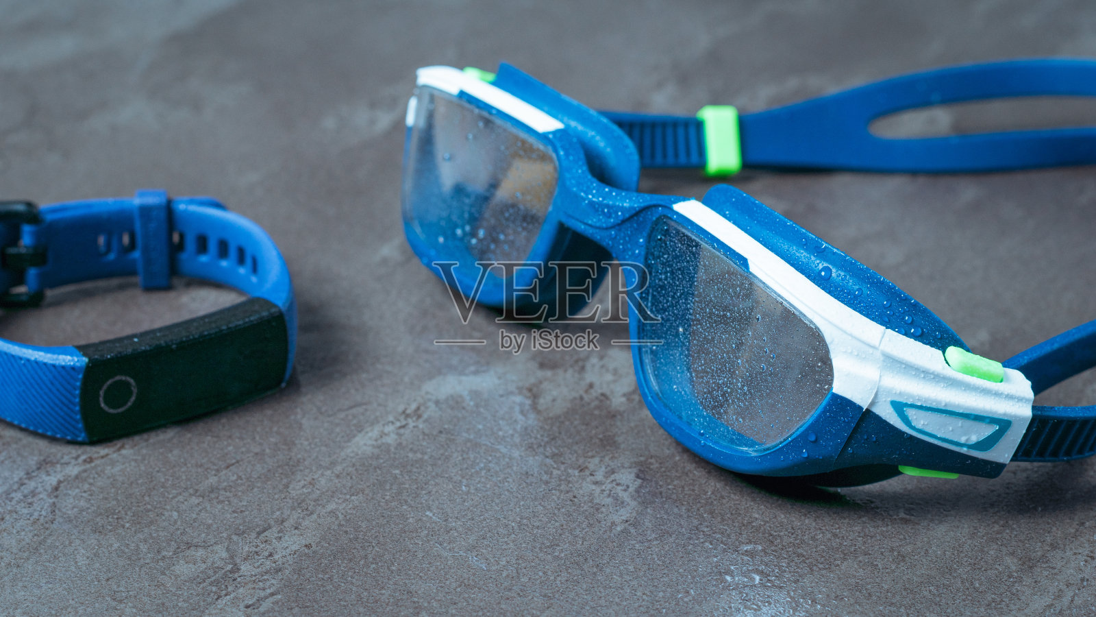 石头背景上的湿泳镜和健身手镯。照片摄影图片