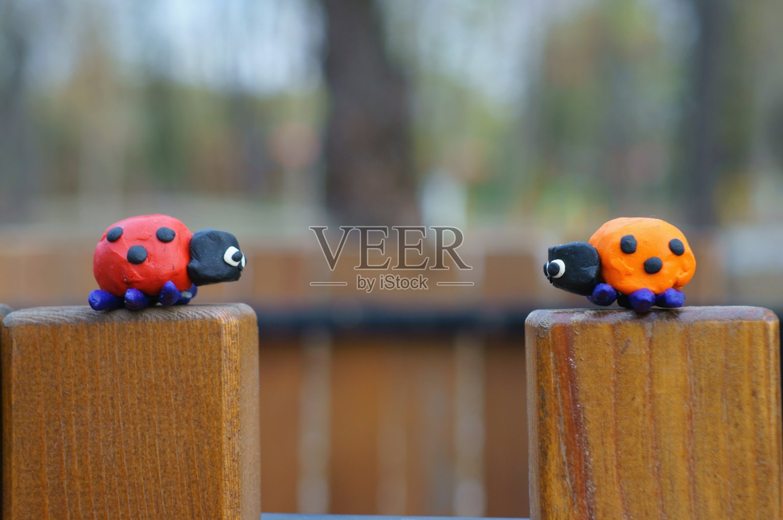 两个橡皮泥做的瓢虫在一个木凳上。照片摄影图片