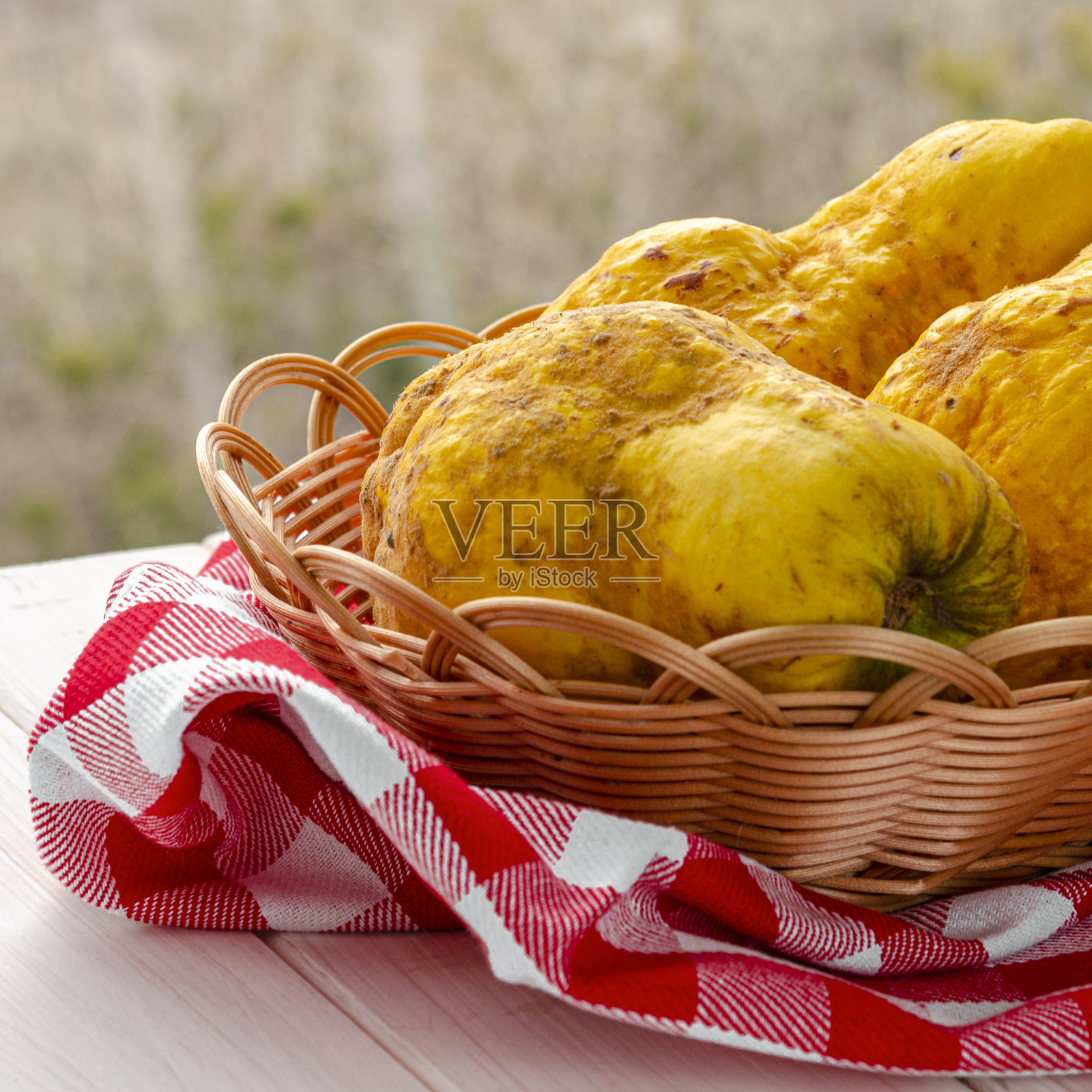 白木桌上的柳条篮子里放着一株大而多汁的黄色伊娃和梨的杂交品种照片摄影图片