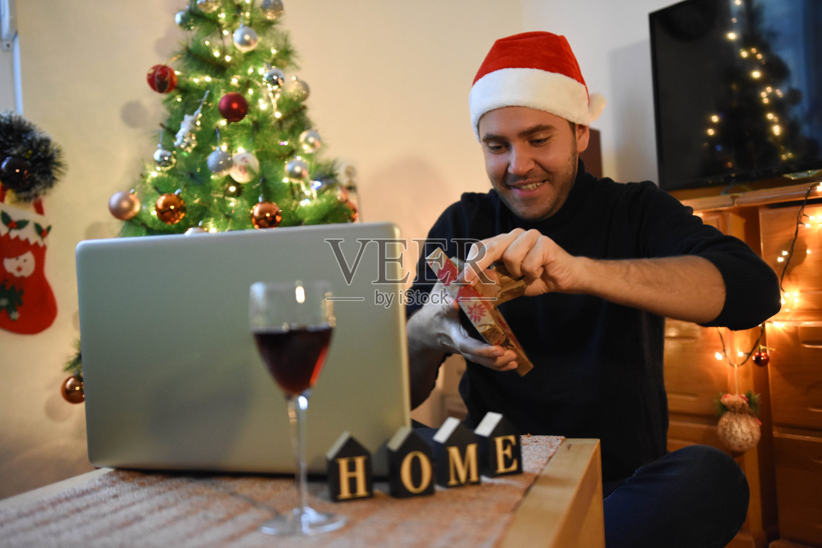 快乐的年轻人打开礼物盒礼物和感觉超越在新的正常的网上圣诞庆祝派对在家里通过笔记本电脑照片摄影图片