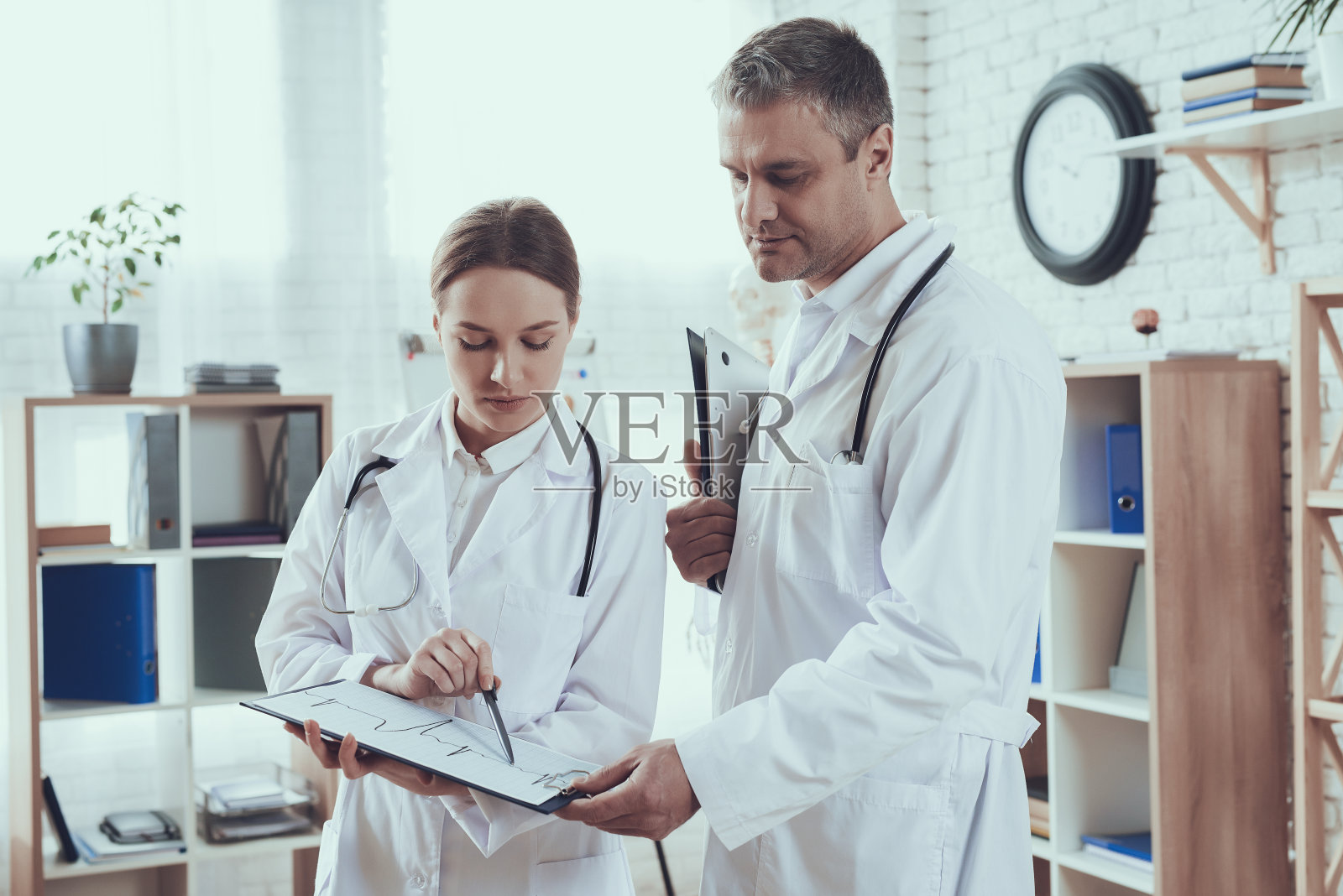 办公室有听诊器的男女医生。医生们正在交换意见。照片摄影图片