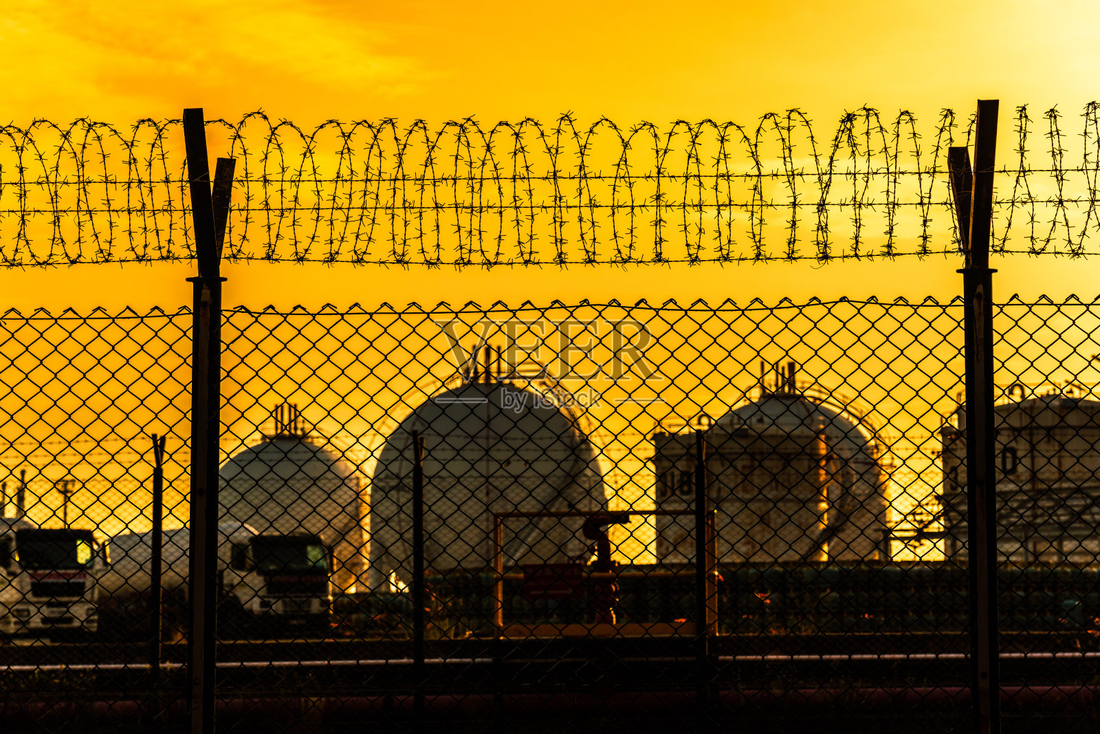 顶部有铁丝网的钢栅栏，保护着燃料储存设施照片摄影图片