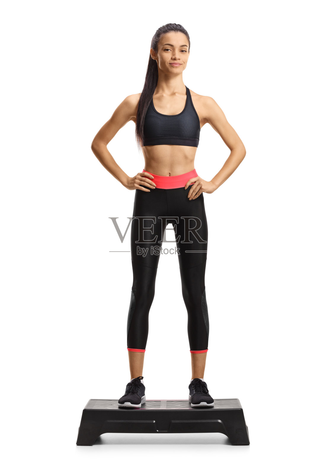 一个苗条的女人站在一个踏步有氧平台的全长肖像照片摄影图片