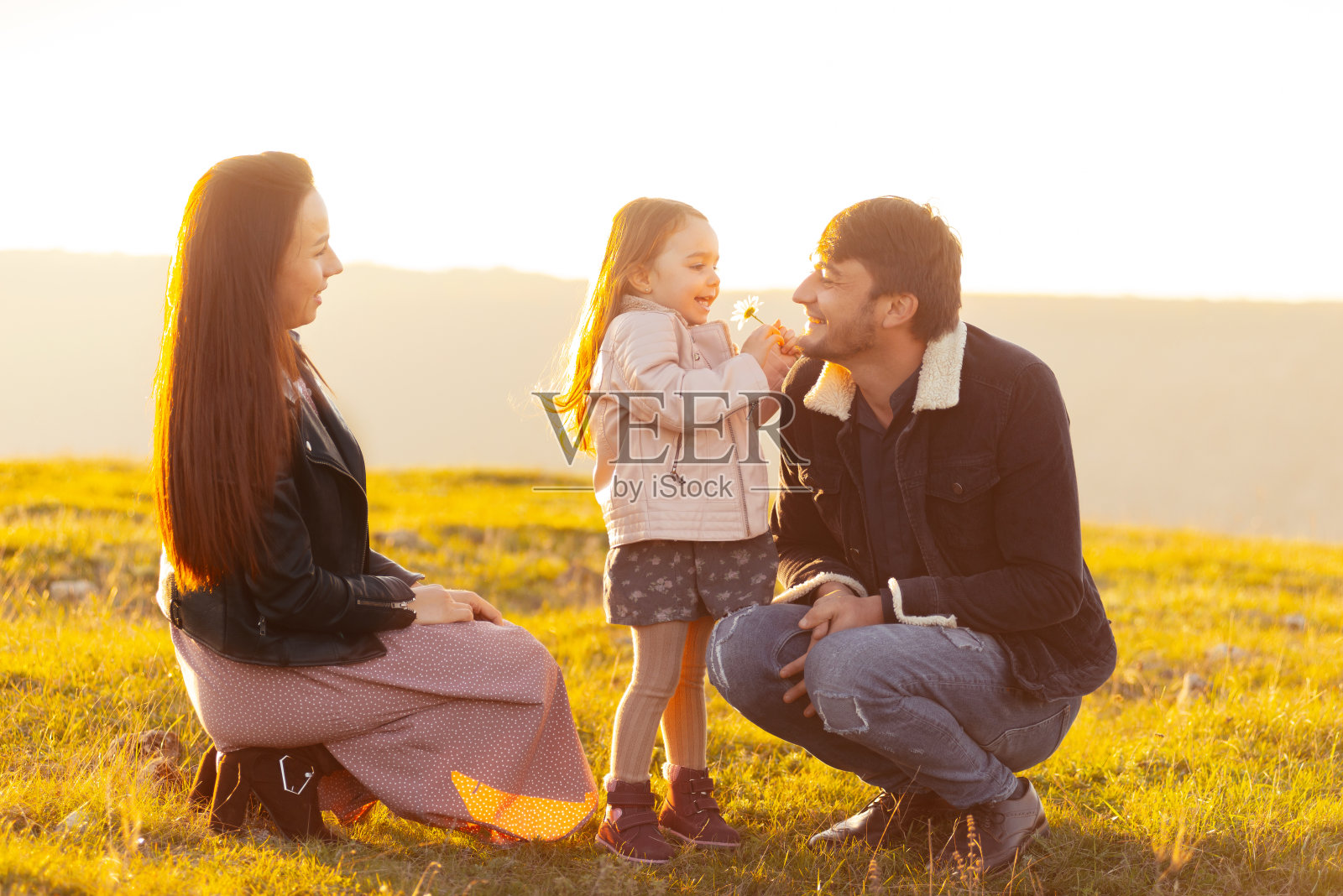 幸福的家庭，爸爸妈妈和女儿一起在大自然中，在夕阳下照片摄影图片