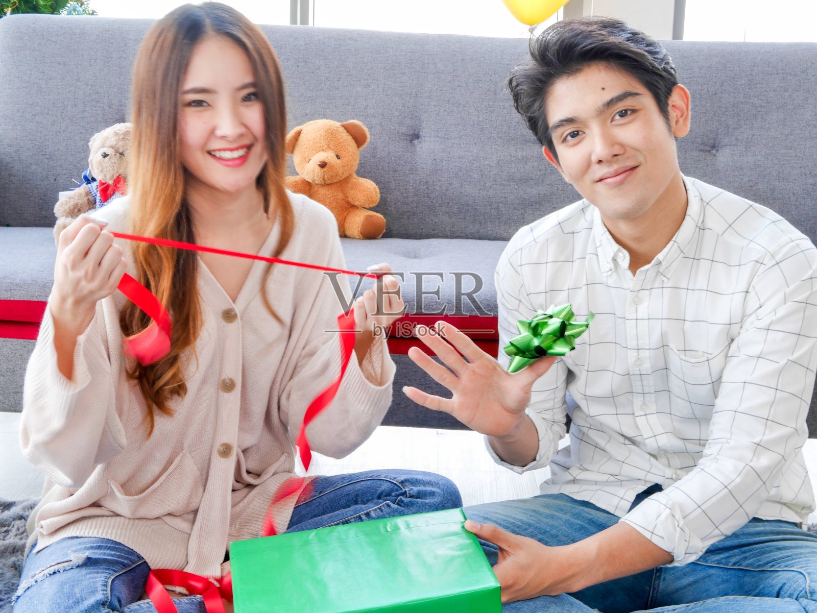 亚洲情侣帮助装饰圣诞树上的装饰品和交换礼盒。照片摄影图片