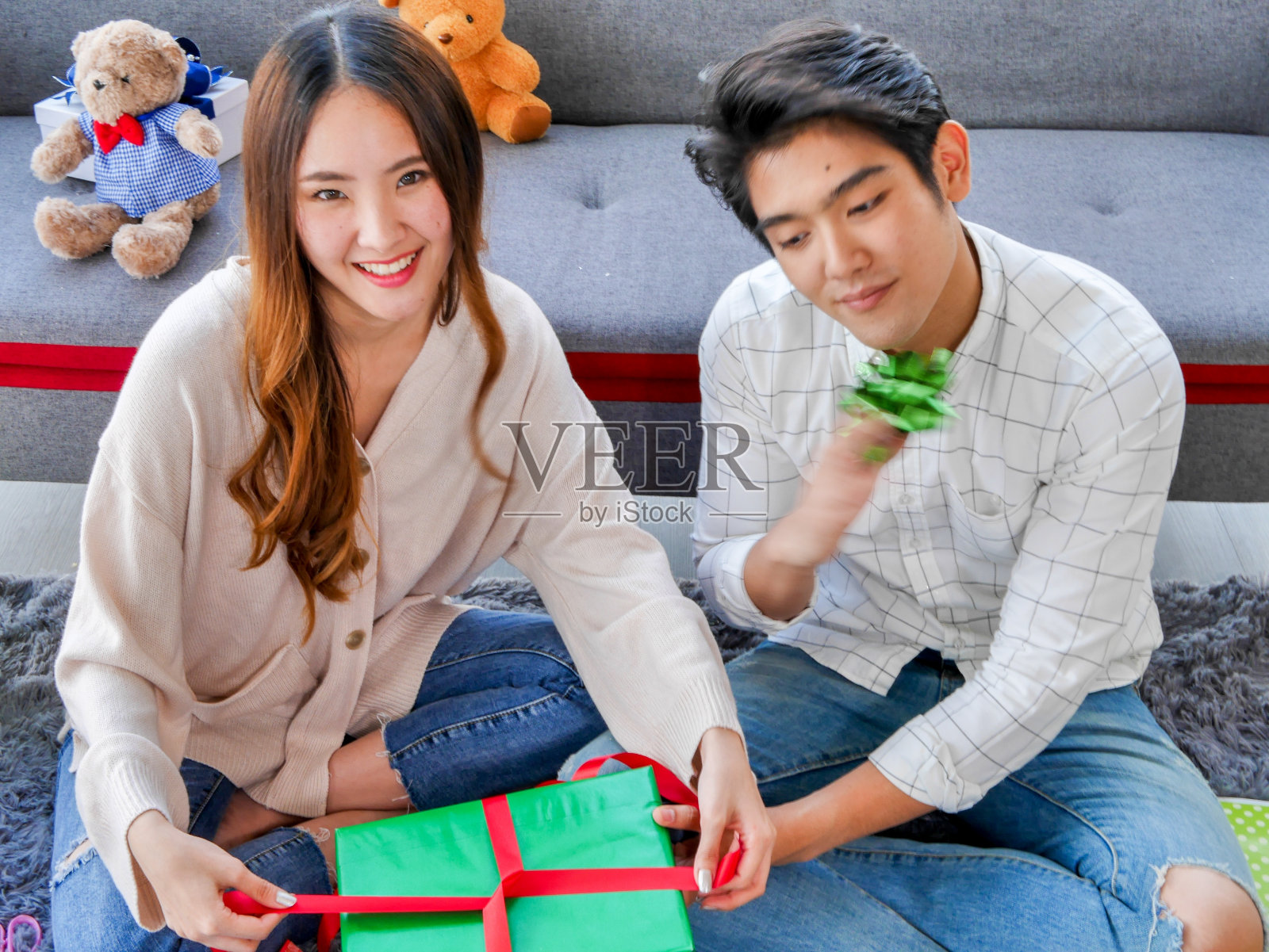 亚洲情侣帮助装饰圣诞树上的装饰品和交换礼盒。照片摄影图片