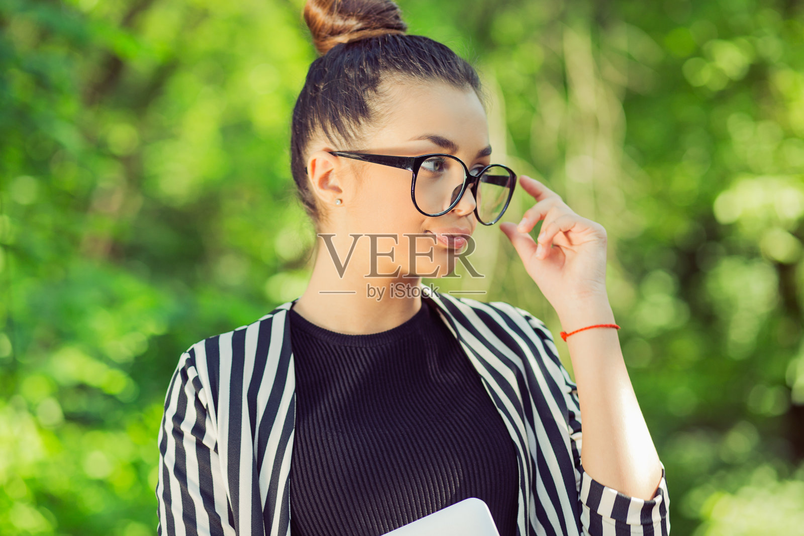 妻子将信将疑地望向一边，带着笔记本电脑在一个城市公园的绿色自然背景下照片摄影图片