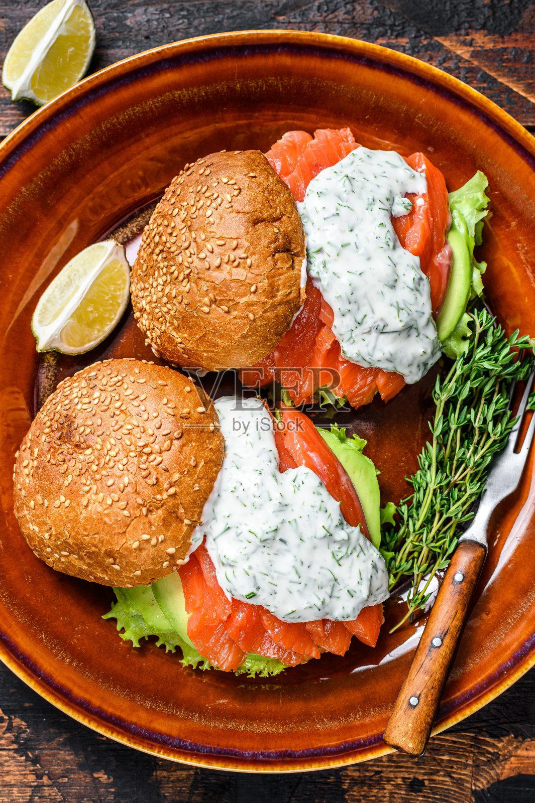 鱼堡配咸鱼三文鱼，牛油果，汉堡面包，芥末酱和冰山沙拉。深色木制背景。俯视图照片摄影图片