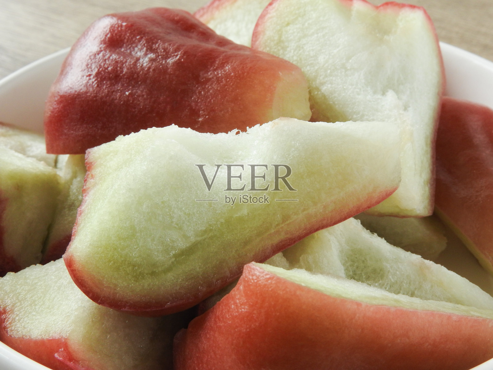 近距离的新鲜切片蜡苹果(也称为玫瑰苹果)板上木制的背景。水果和农业概念。照片摄影图片