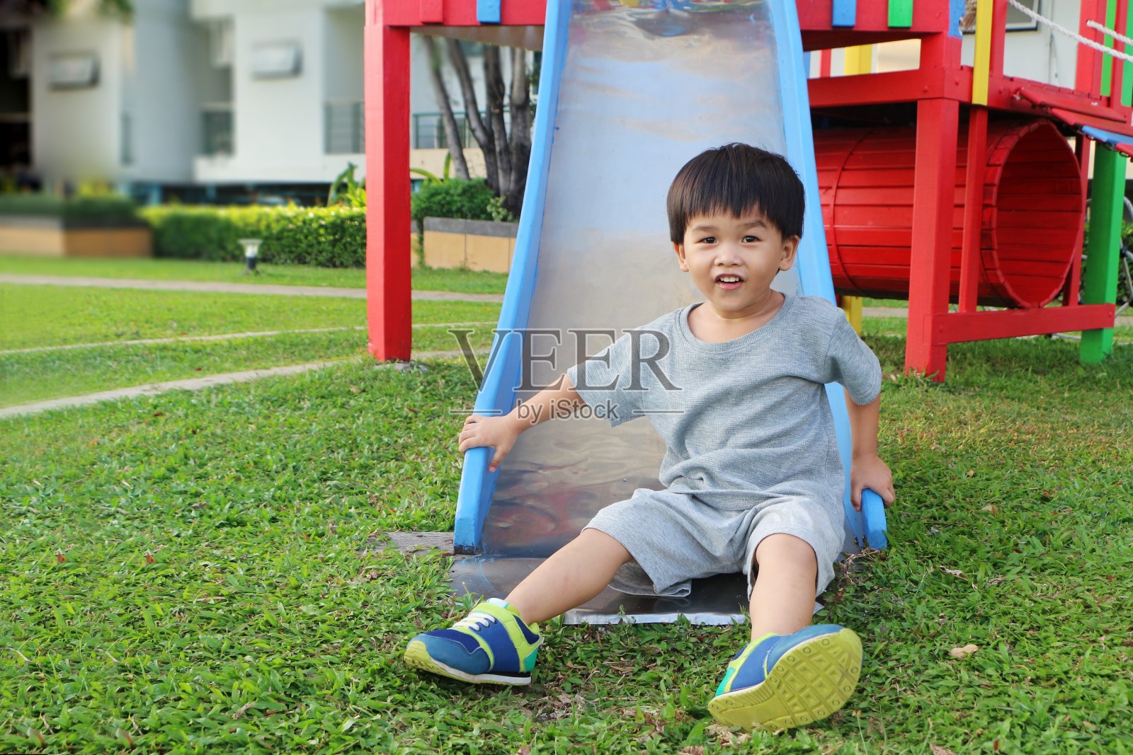 小男孩在操场上玩滑梯。照片摄影图片