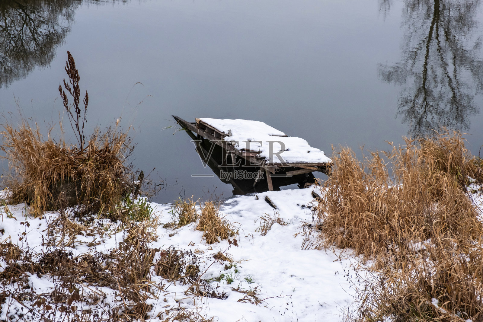 一座被雪覆盖的断桥，河岸上长满了枯黄的草。照片摄影图片