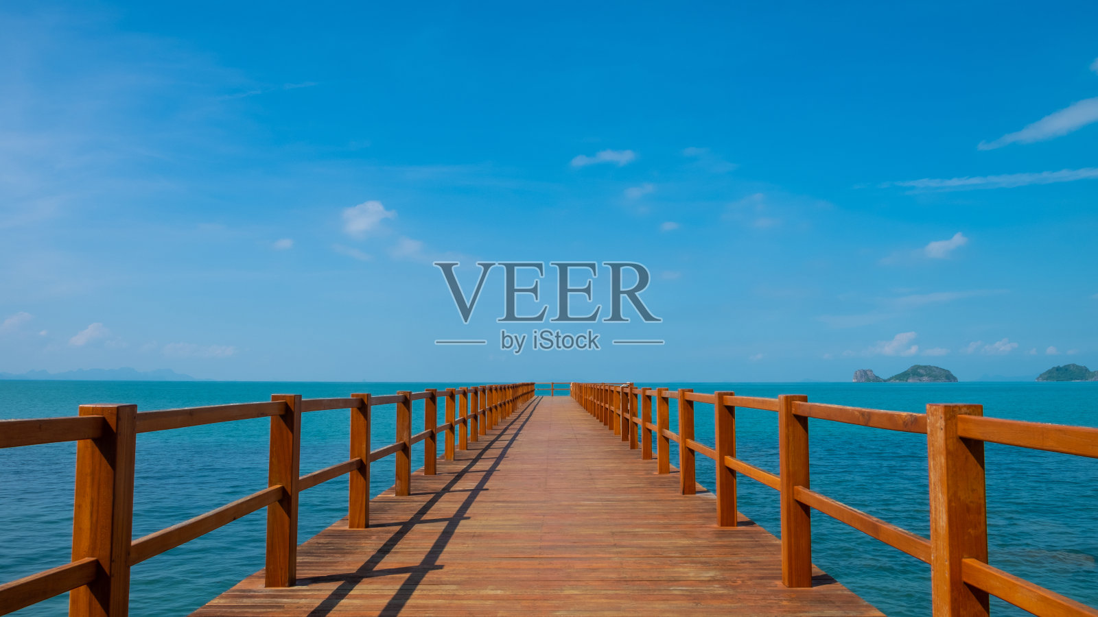 室外，景观拍摄的木制步道进入海洋中央。蓝天白云，海景岛景。热带旅游目的地理想的背景与复制空间。照片摄影图片