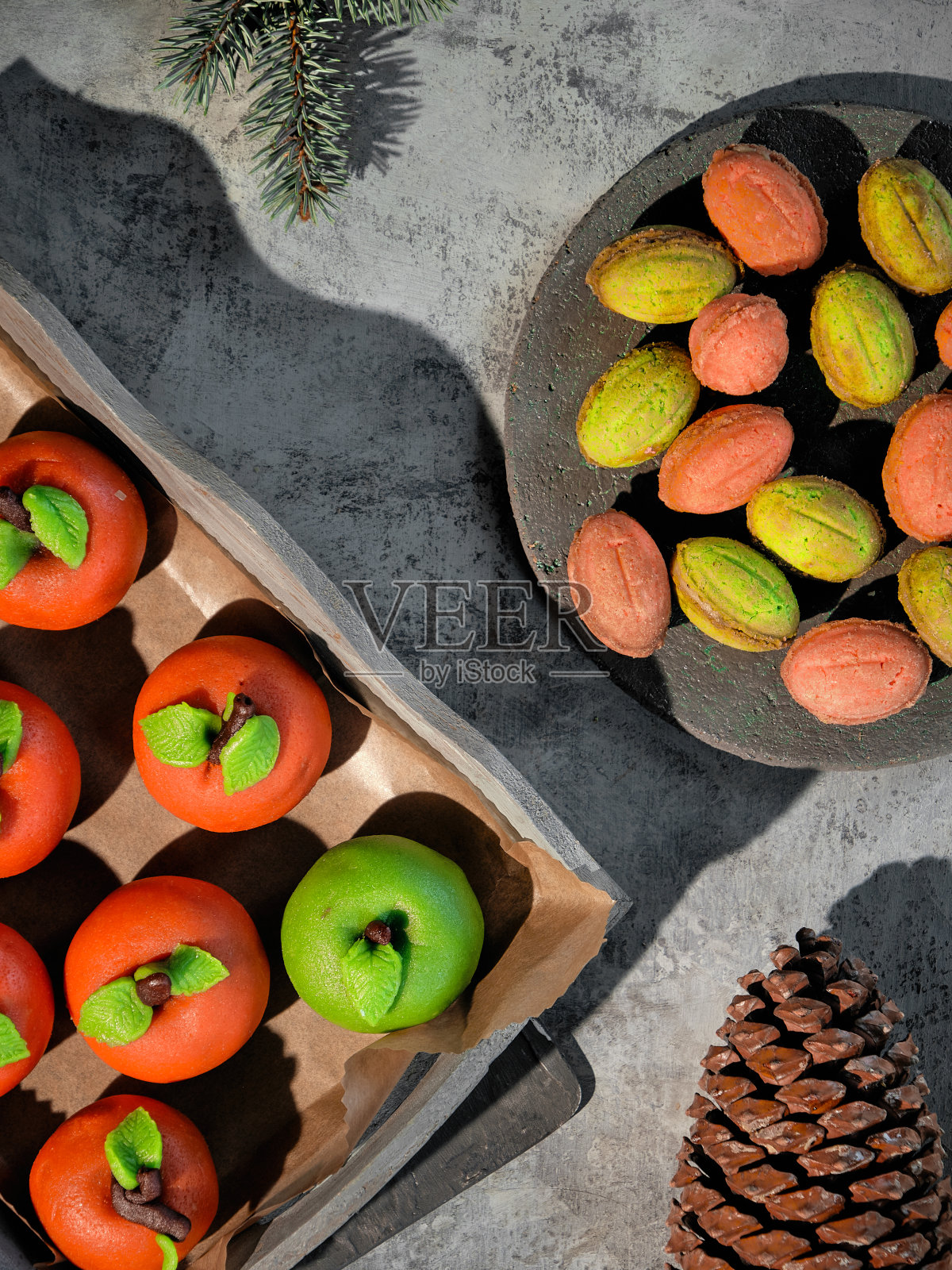 杏仁软糖苹果和甜炼乳核桃。美味的创意甜点搭配绿色和红色的乡村木材。平躺着，长长的影子照片摄影图片