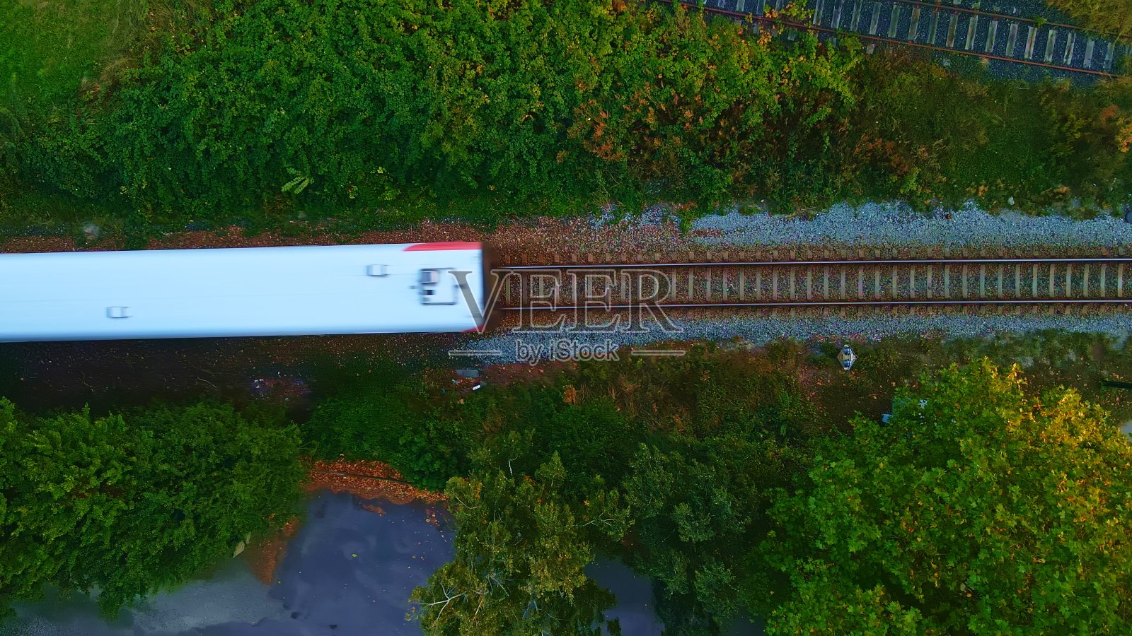 一列白人旅客列车在铁轨上驶过。鸟瞰图。照片摄影图片