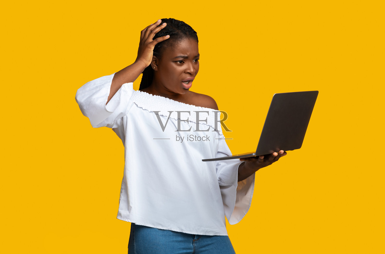 困惑的年轻黑人妇女拿着笔记本电脑，电脑有问题照片摄影图片