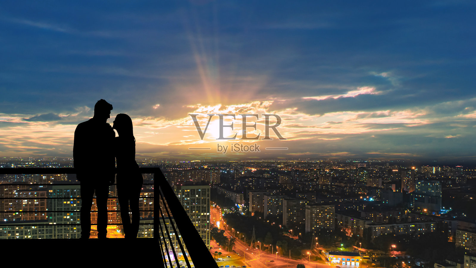 这对浪漫的情侣站在以城市为背景的阳台上照片摄影图片