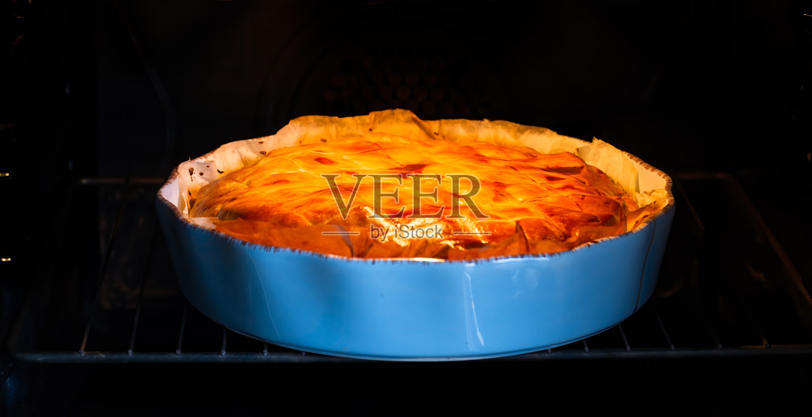 烤土豆派在烤箱，在蓝色陶瓷馅饼锅照片摄影图片