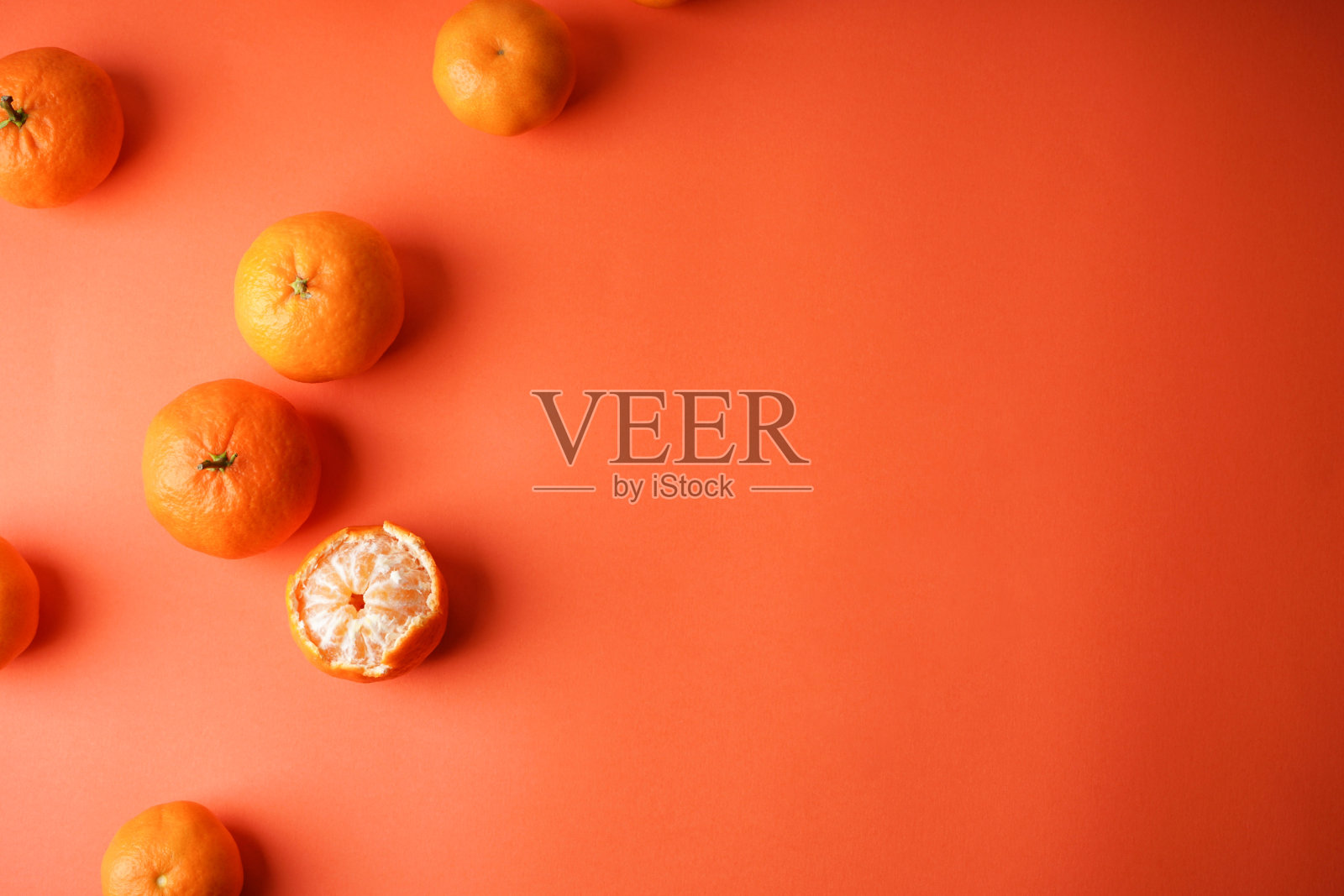 成熟的橘子，其中一个去皮了，在橙色的背景下，文字平铺。照片摄影图片