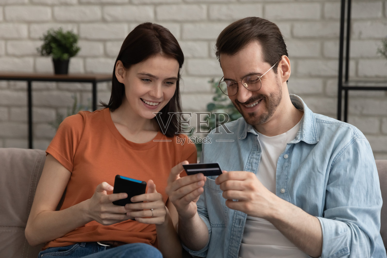 微笑的千禧白种人夫妇购物在移动应用程序。照片摄影图片