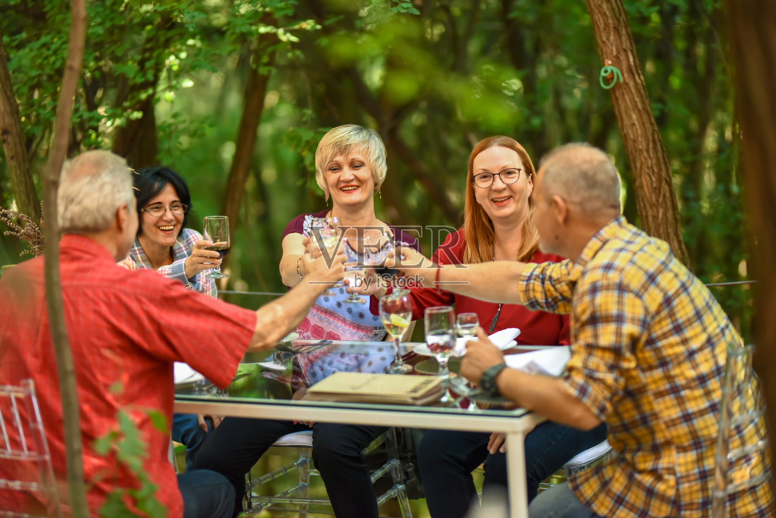 森林环境中的餐厅。快乐成熟的朋友们一起吃饭。照片摄影图片