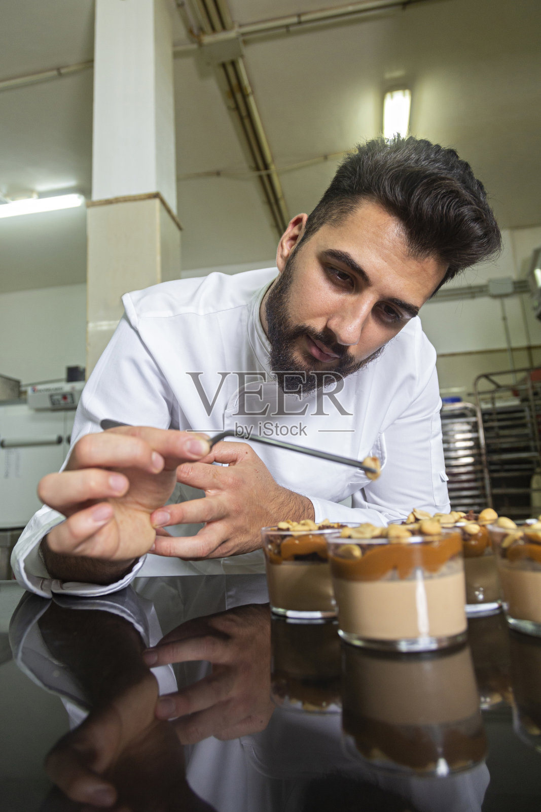 糕点师正在用玻璃杯做甜点。照片摄影图片