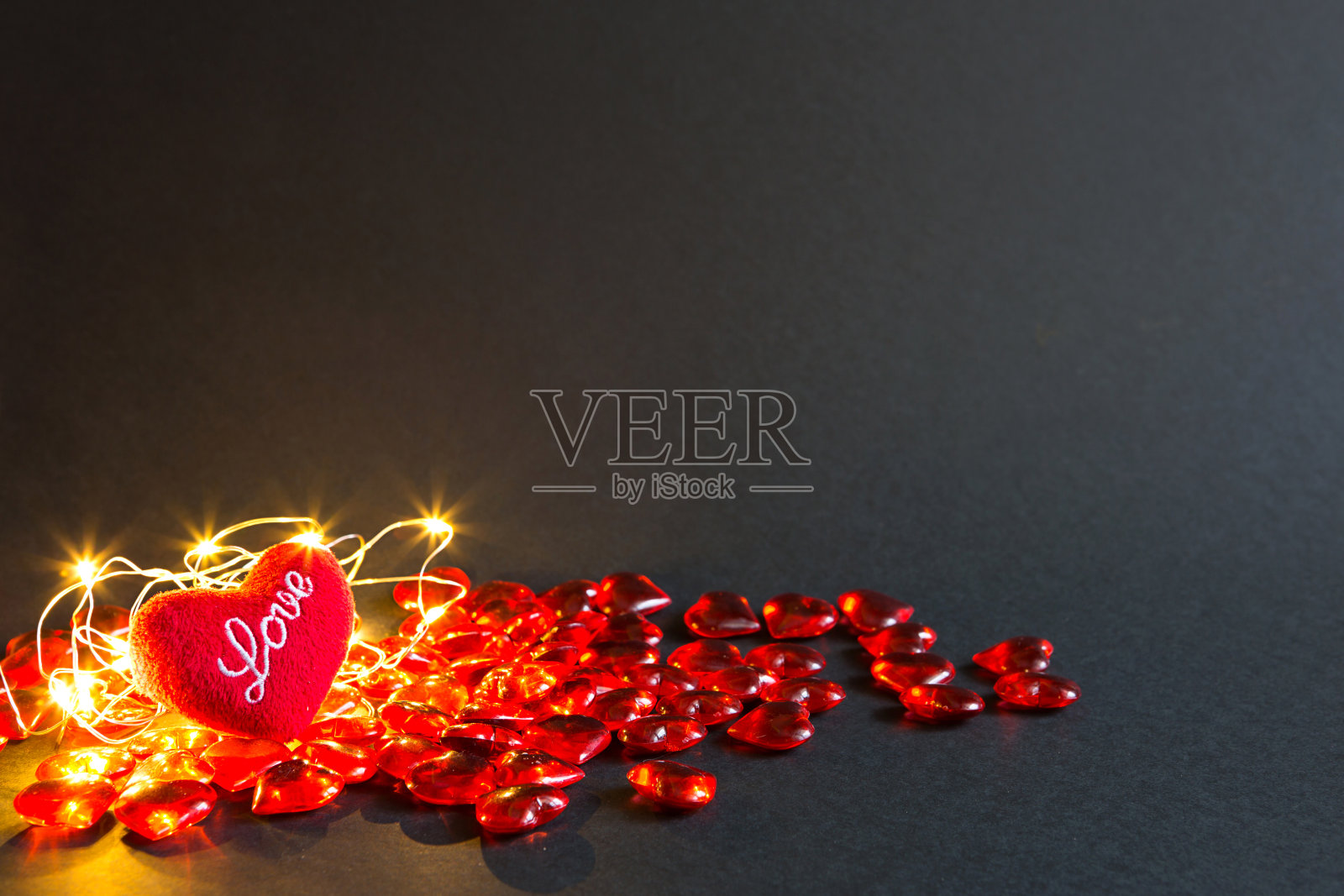 红色的玻璃心和柔软的毛绒心，黑色的背景上写着“爱”，金色的灯-情人节。节日,旗帜,copyspace。购物和礼物，礼物给相爱的人，相爱的夫妇照片摄影图片